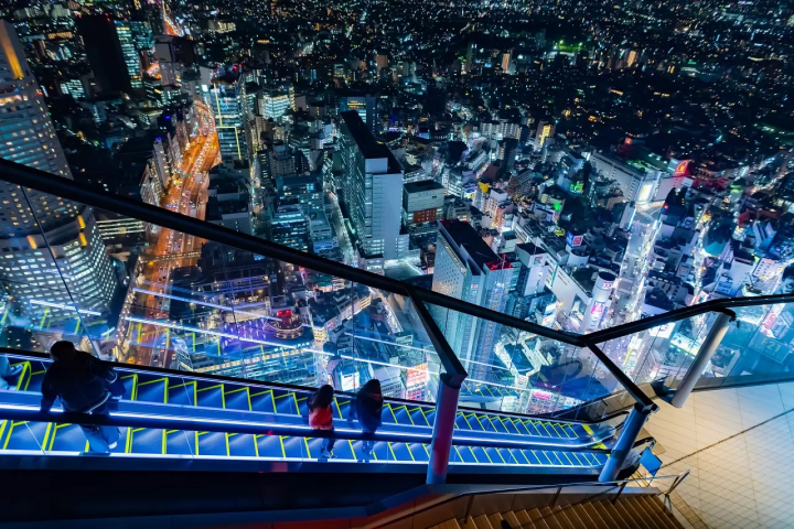 Visitors on the Shibuya Sky rooftop with city lights