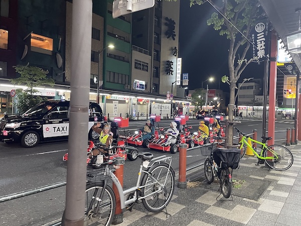 A convoy of red street go-karts driving through Asakusa at night